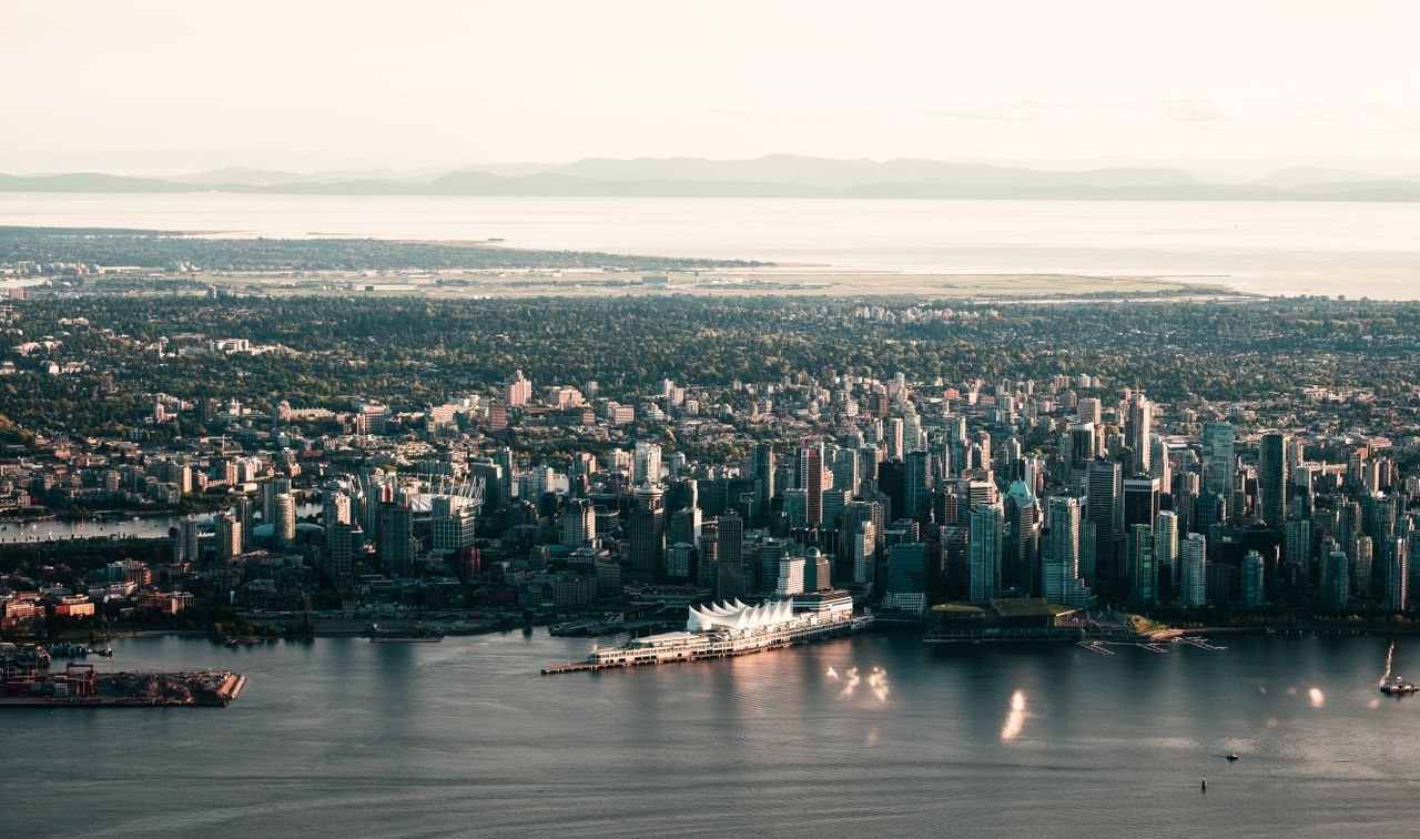 Scenic aerial shot of Vancouvers skyline with waterfront and mountains in the background.